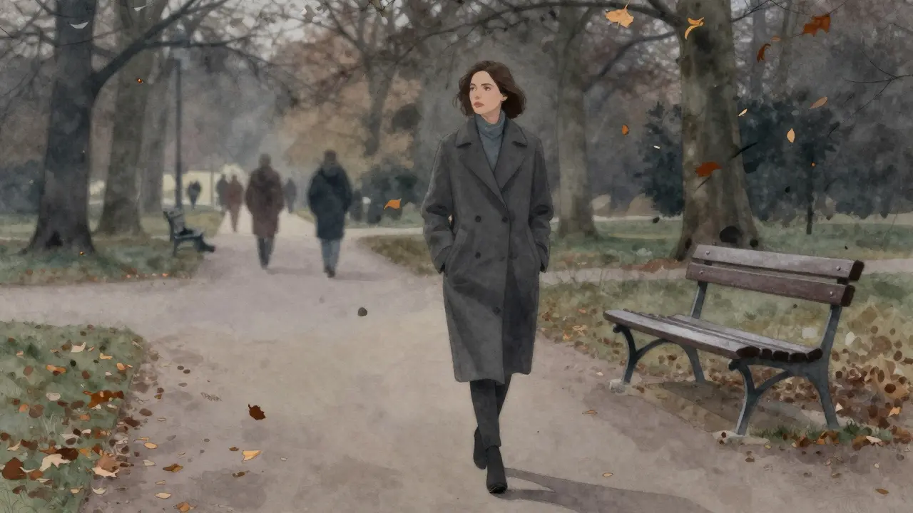 A woman walking alone through Tiergarten park at dusk, autumn leaves falling around her.